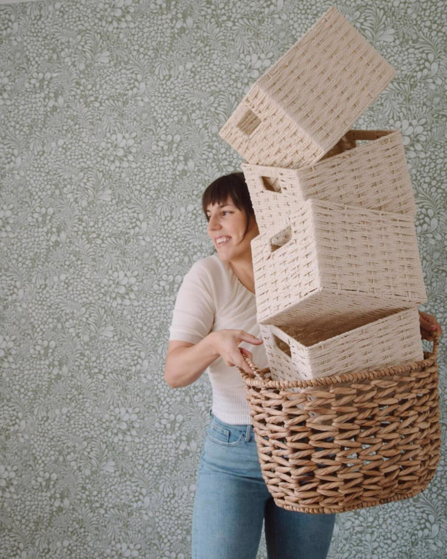 a professional organizer balancing baskets to a towering height which represents all services offered, including space planning, decluttering, and organizing